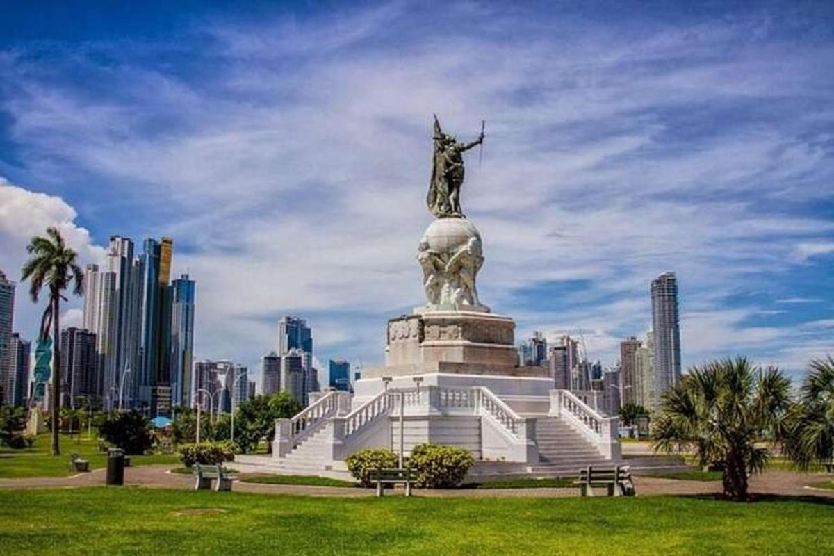 una estàtua en un parc amb una ciutat al fons