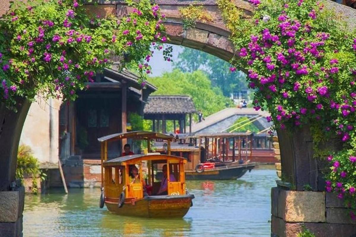a small boat in the water under a bridge with flowers