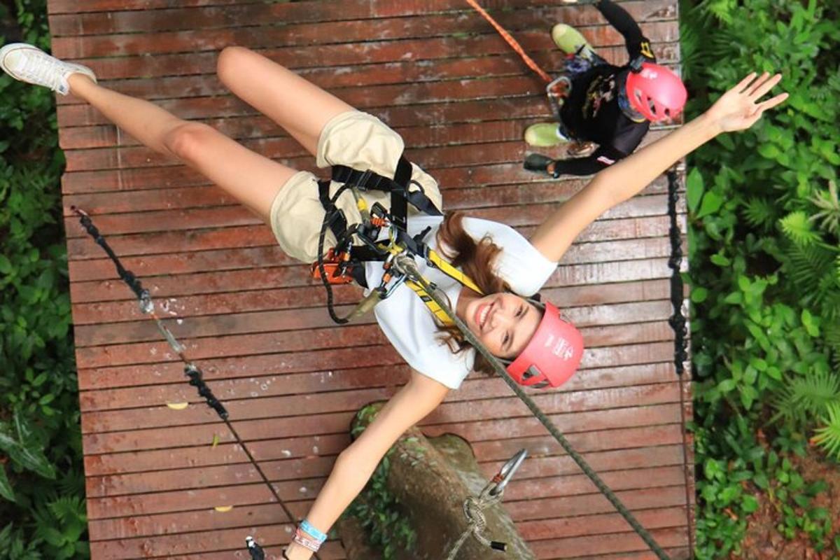 two girls in helmets are hanging on a zip line