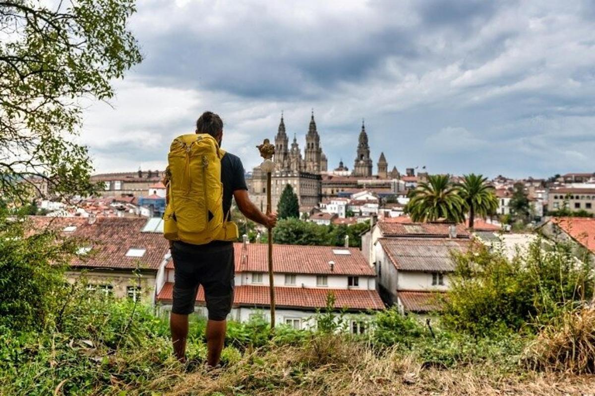 um homem com uma mochila amarela olhando para uma cidade