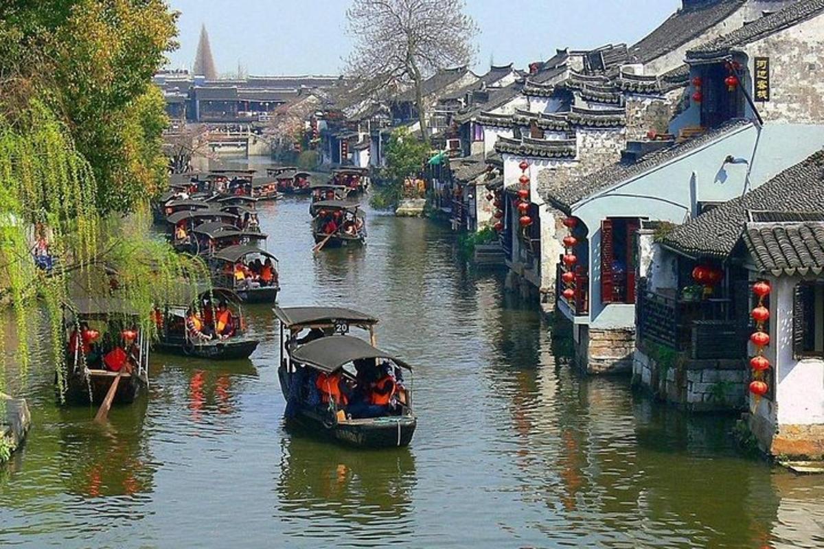 Un grupo de barcos viajando por un río con edificios.