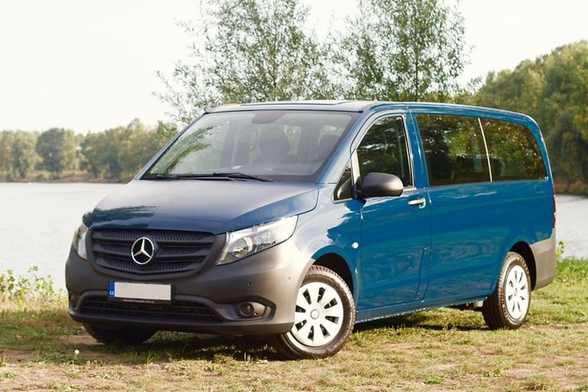 a blue van parked in a field next to a lake