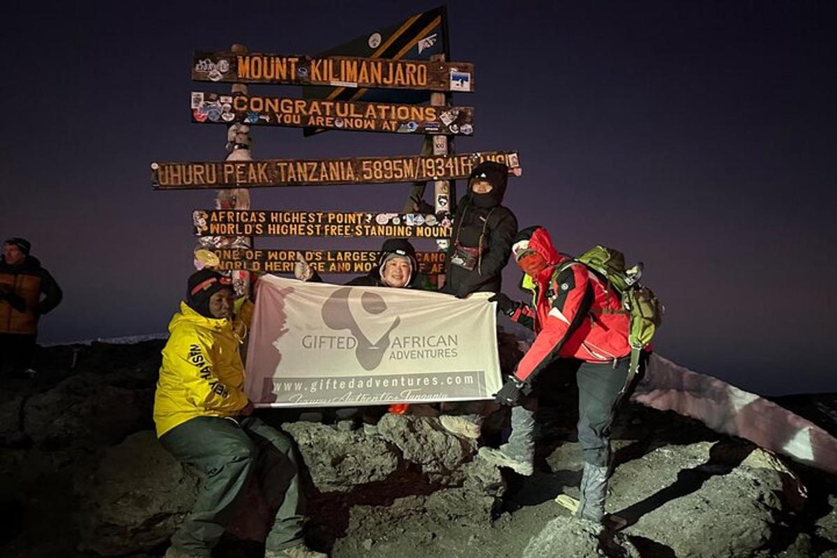 a group of people holding a sign on top of a mountain