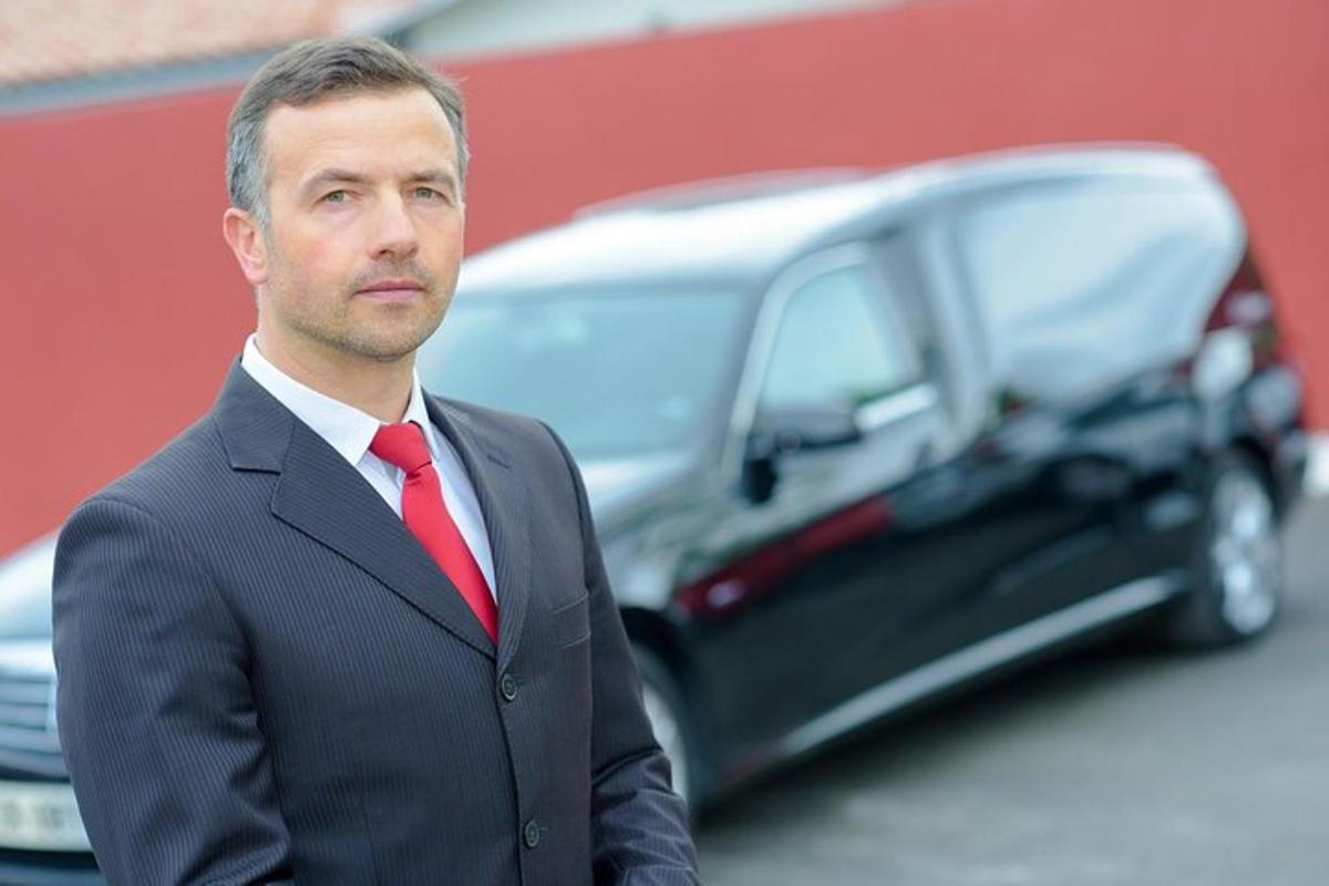 a man in a suit and tie standing in front of a car