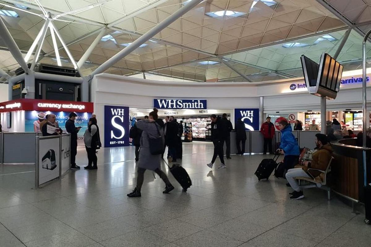 a group of people walking through an airport with their luggage