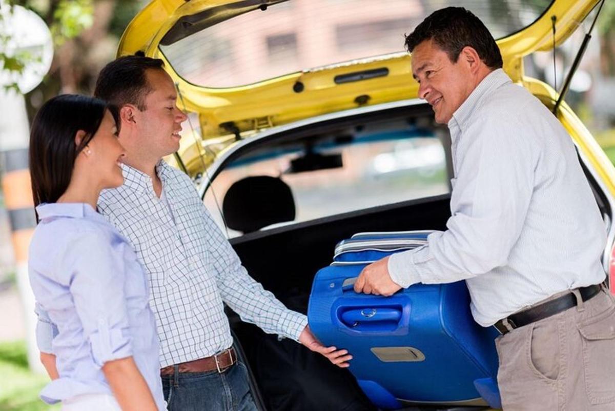 dois homens e uma mulher segurando uma mala no porta-malas de um carro