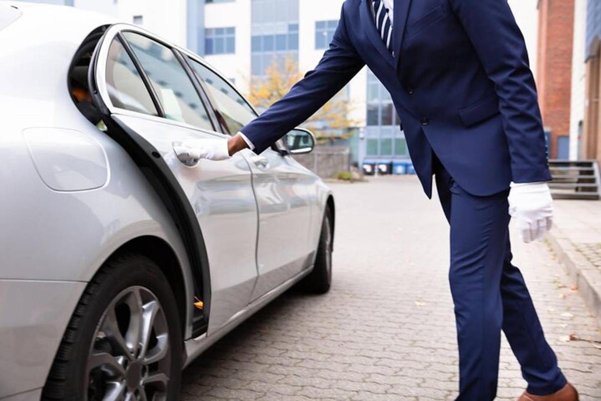 un homme en costume debout à côté d'une voiture
