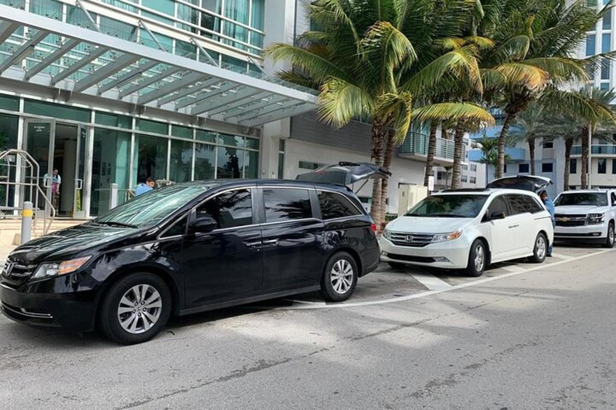 dua buah kereta diletakkan di hadapan sebuah bangunan dengan pokok palma