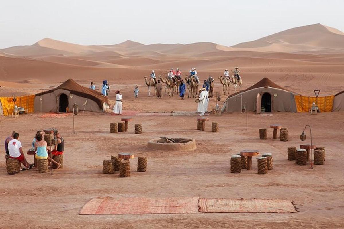 un grup de persones en un desert amb tendes i camells