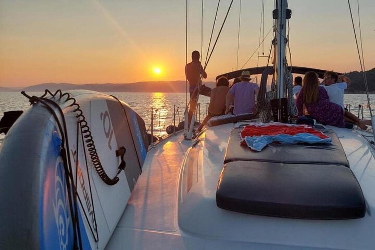 a group of people sitting on a boat at sunset