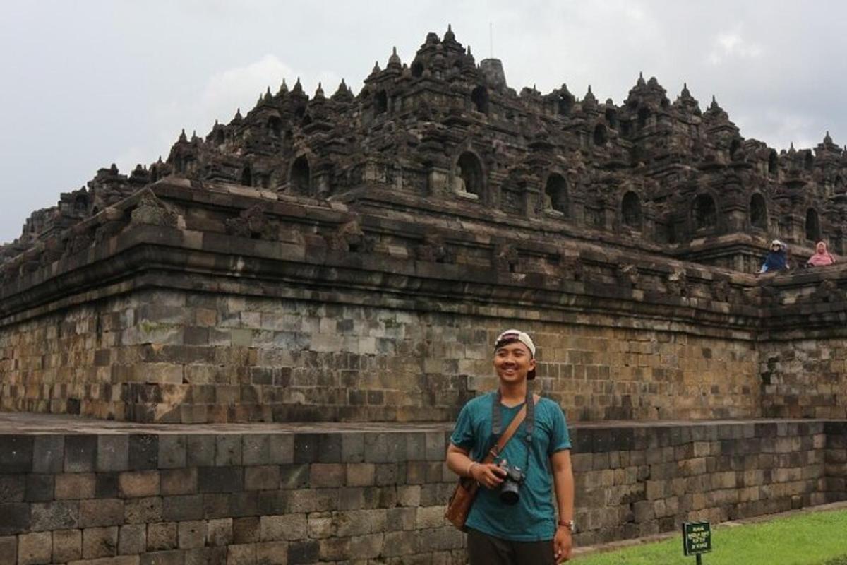 a man standing in front of a stone wall