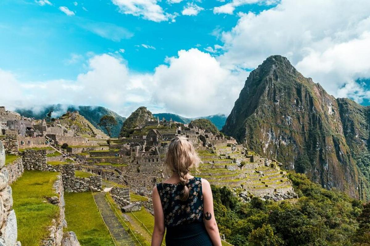 een vrouw die op de ruïnes van Machu Picchu in de bergen staat