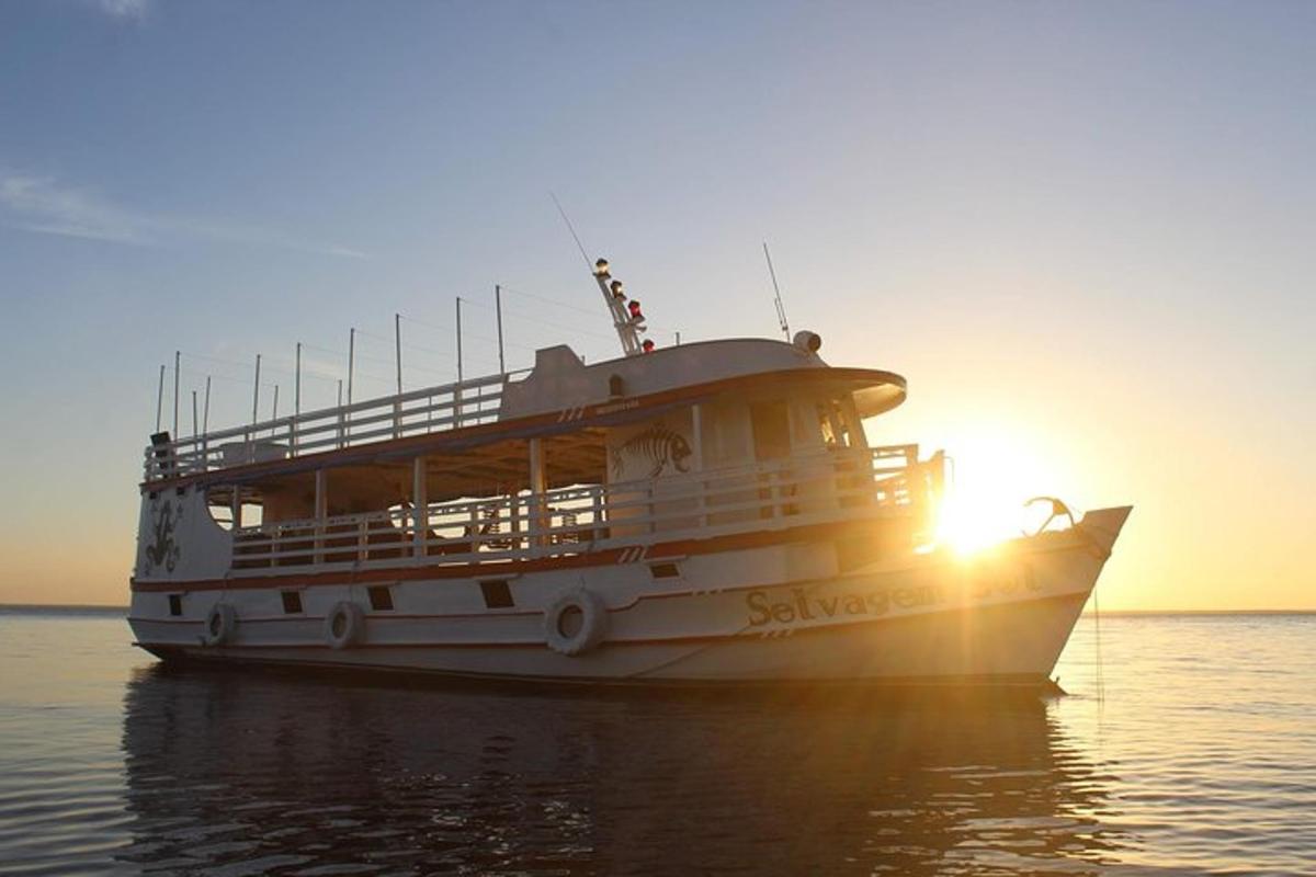a white boat in the water with the sun setting