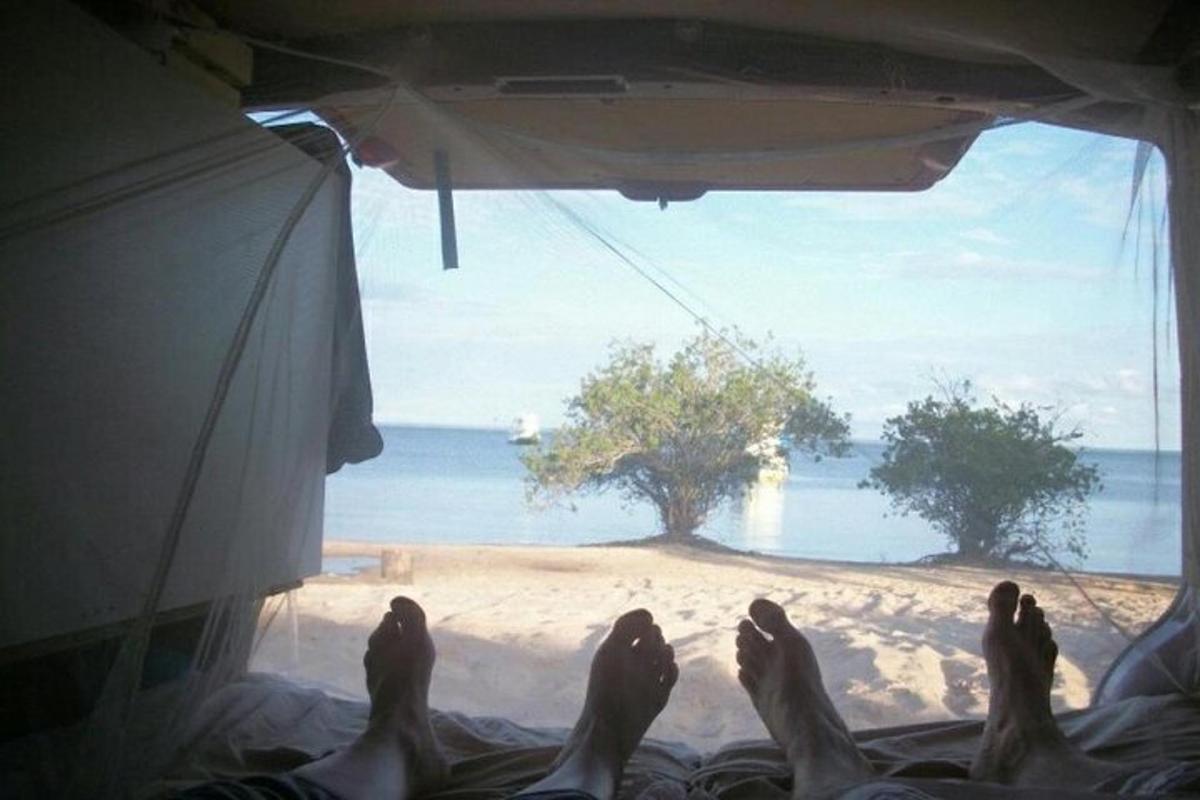a person laying in a tent looking out at the beach