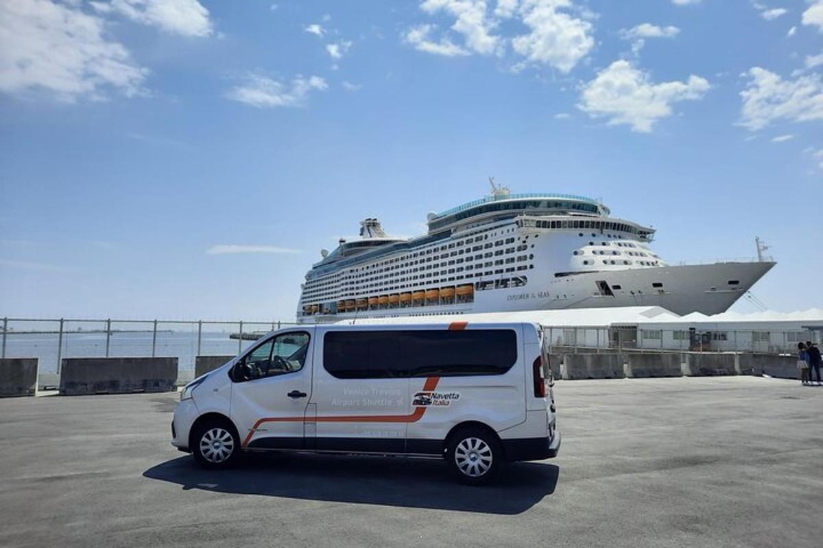 ein weißer Lieferwagen, der vor einem Kreuzfahrtschiff geparkt ist
