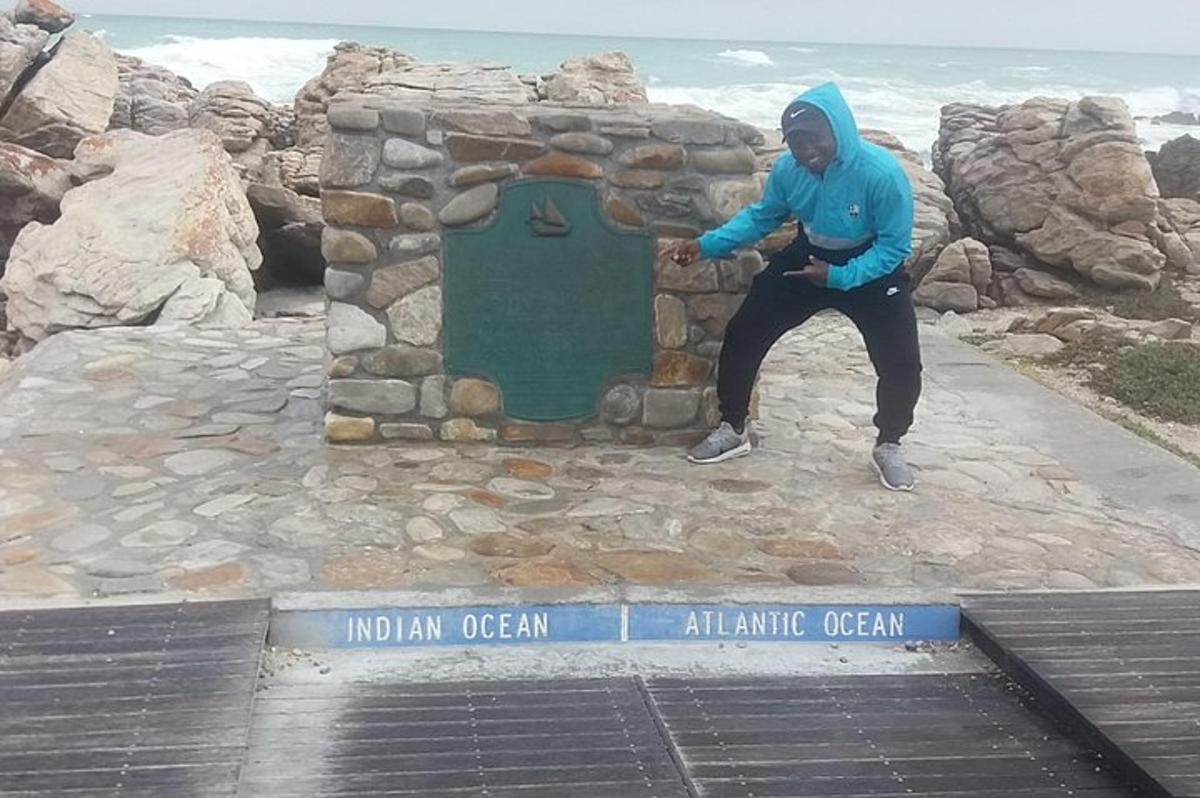 um homem parado ao lado de uma placa no oceano