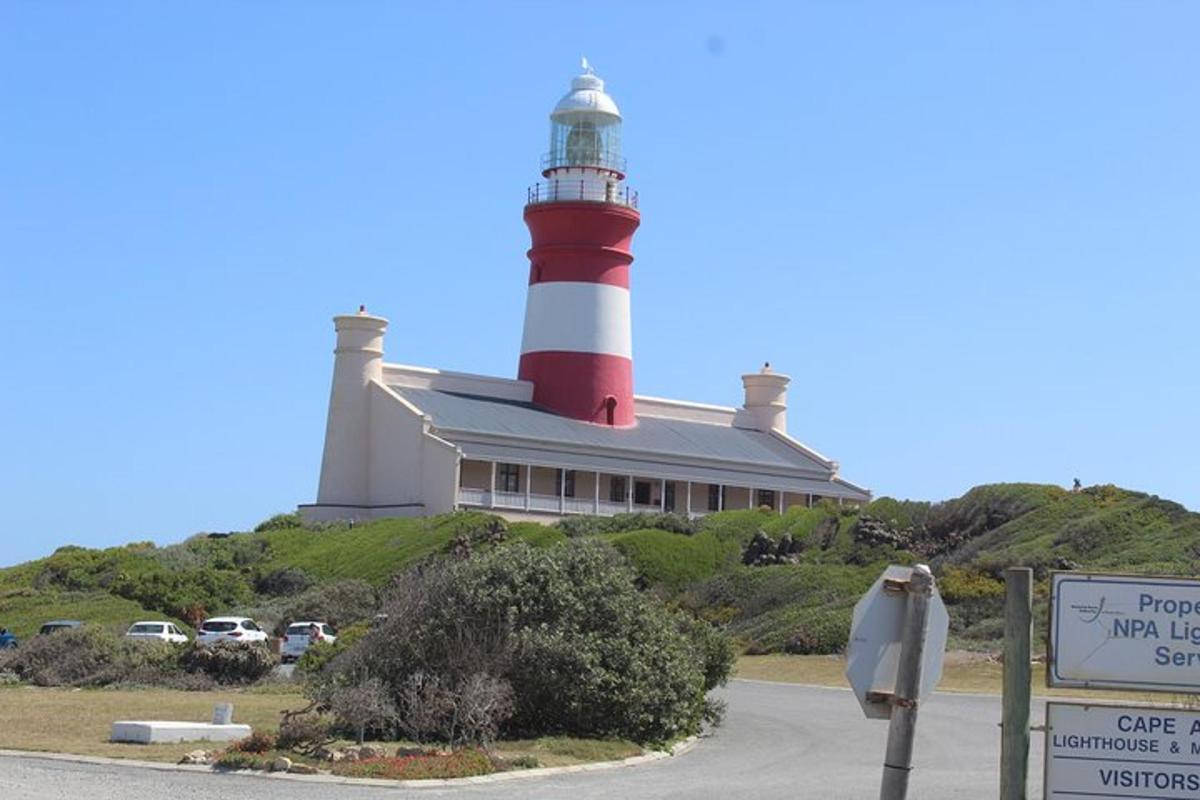 um farol no topo de uma colina com uma placa