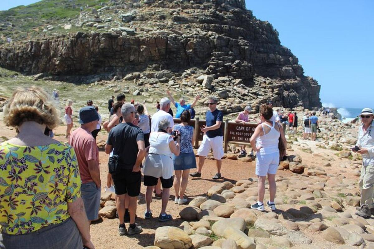 um grupo de pessoas em pé ao redor de uma placa na praia