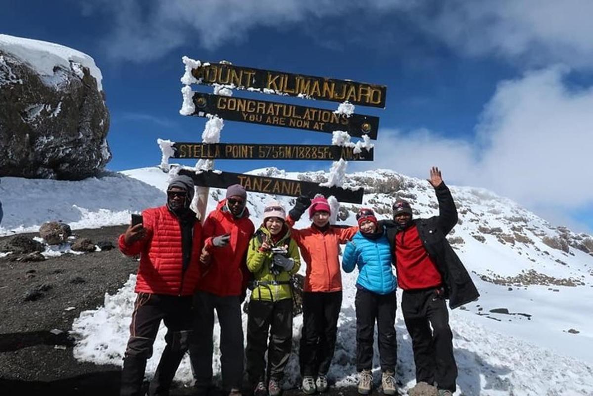 um grupo de pessoas em pé em frente a uma placa em uma montanha