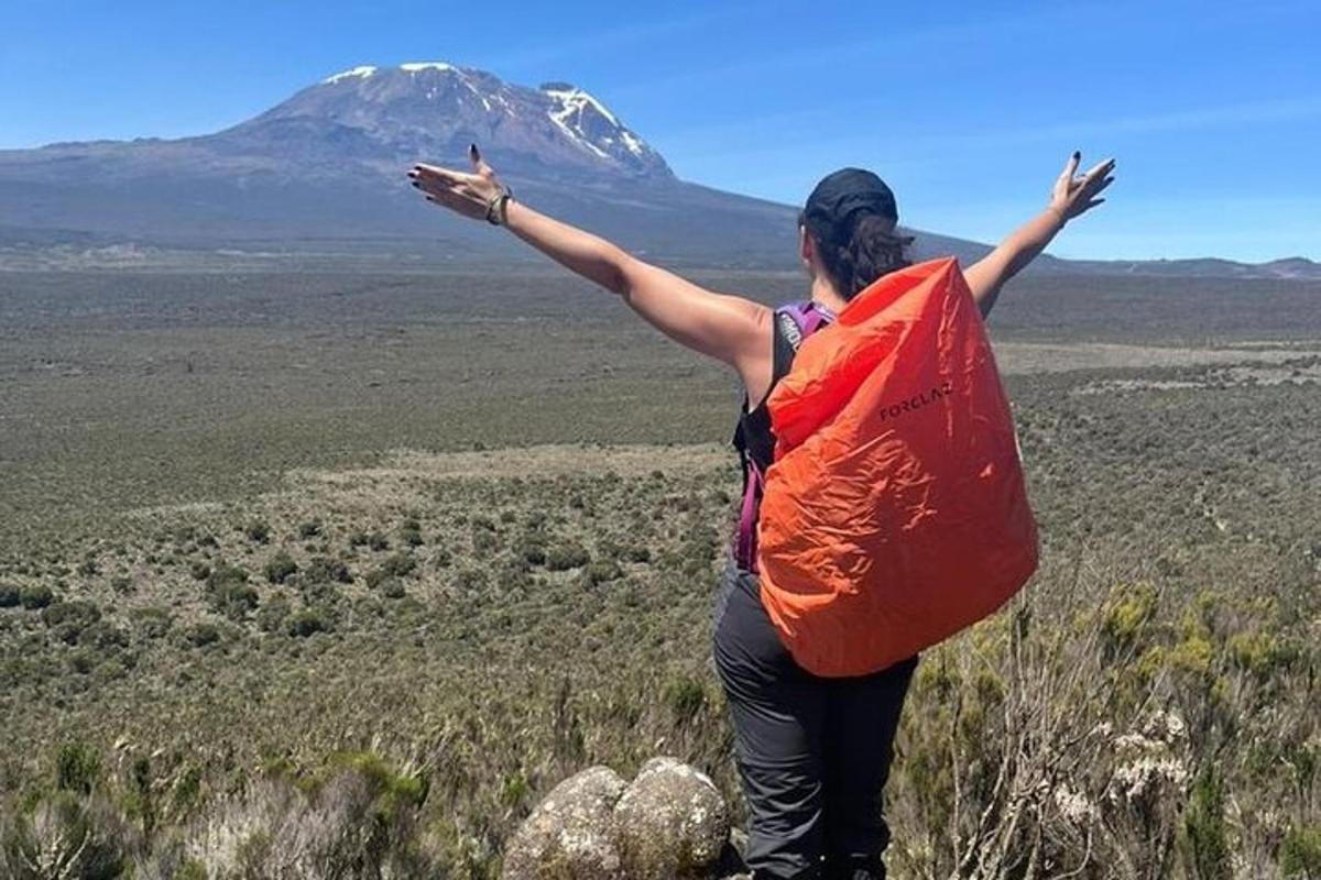 um homem em pé no topo de uma montanha com os braços estendidos