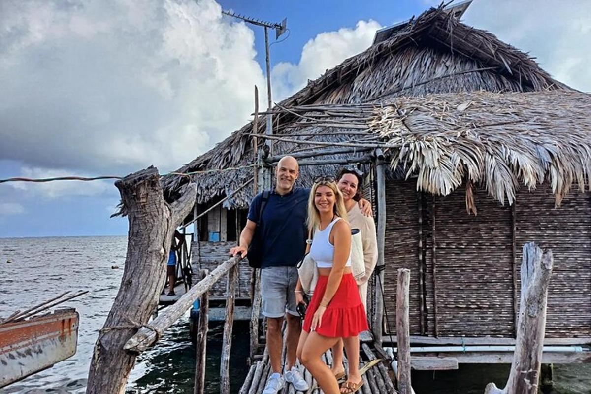 a group of three people standing on a pier in front of a hut