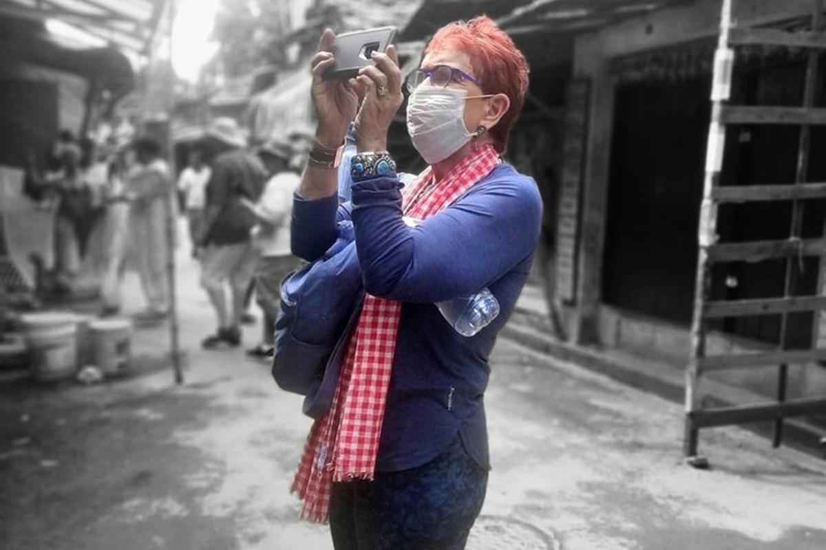 a woman wearing a mask taking a picture with her cell phone