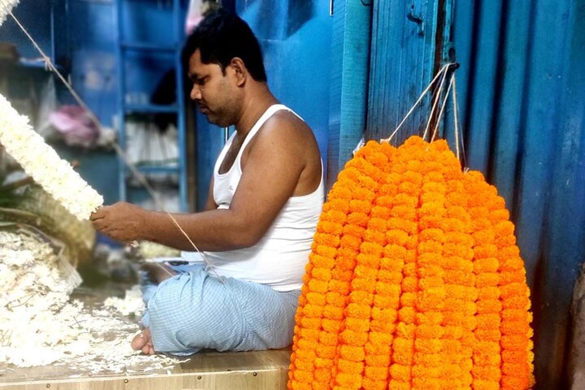 um homem sentado ao lado de um grande buquê de flores