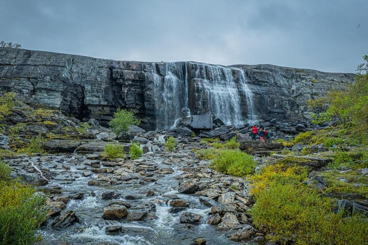 a waterfall with people standing in front of a river