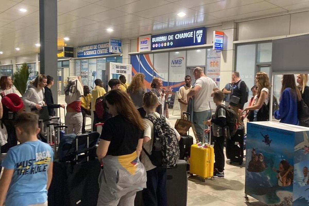 um grupo de pessoas em pé em um aeroporto com bagagem