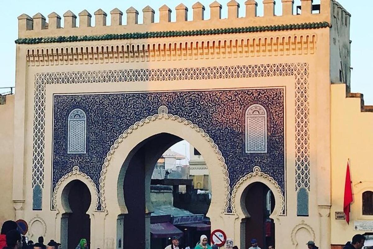 Un edificio con un arco con gente de pie alrededor.