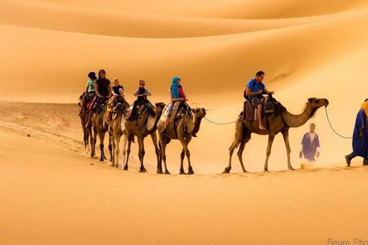 Un grupo de personas montando camellos en el desierto.