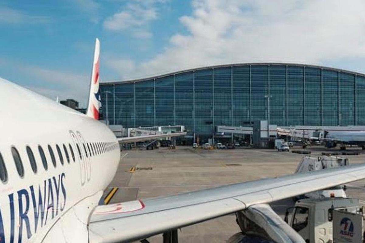 ένα αεροπλάνο παρκαρισμένο σε ένα αεροδρόμιο με ένα κτίριο