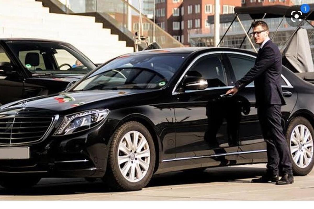 um homem de terno parado ao lado de um carro