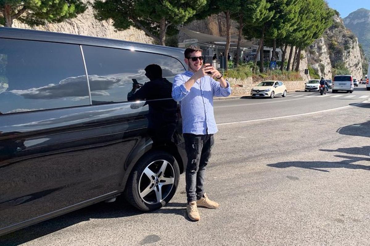 Un hombre parado frente a un auto tomando una foto