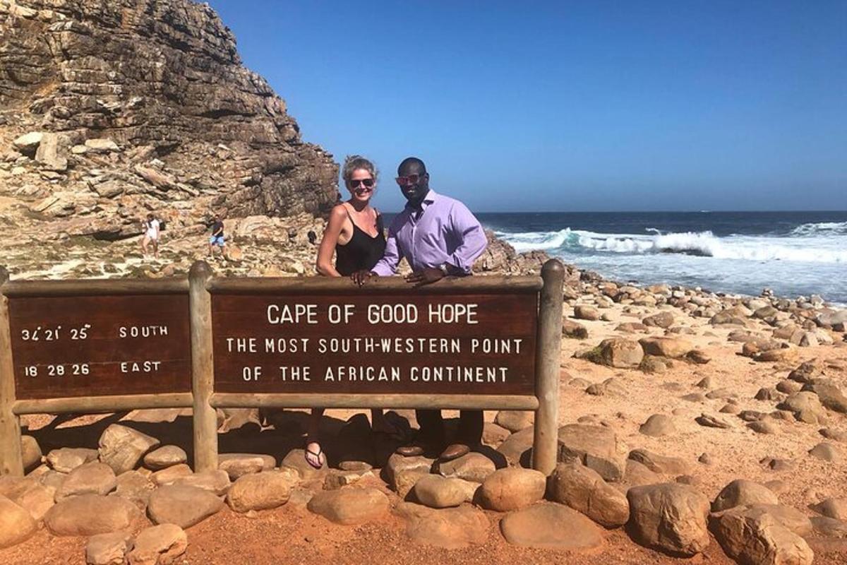 un uomo e una donna in piedi accanto a un cartello sulla spiaggia