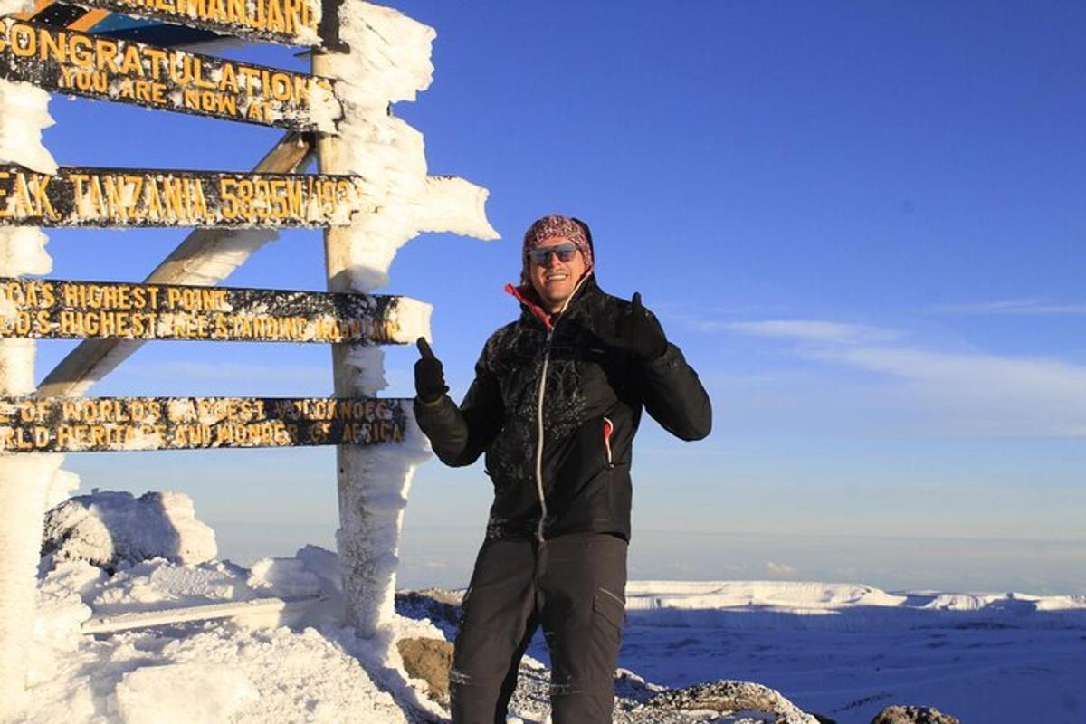 Un hombre de pie junto a un cartel en la nieve.