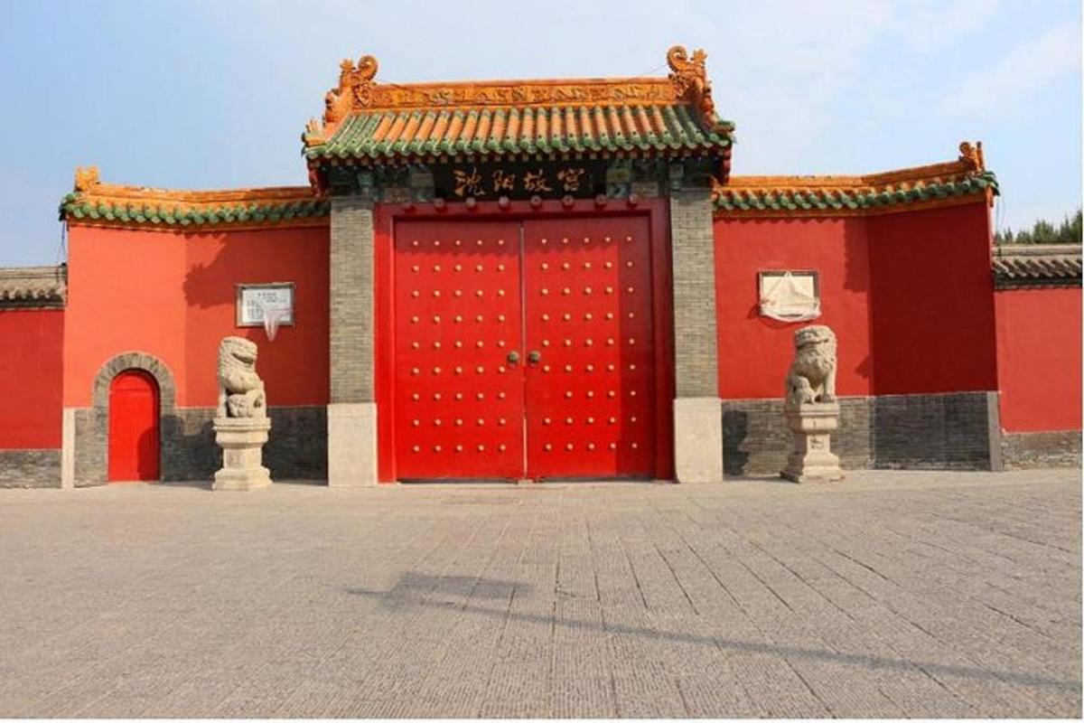 a red building with a red door and two statues