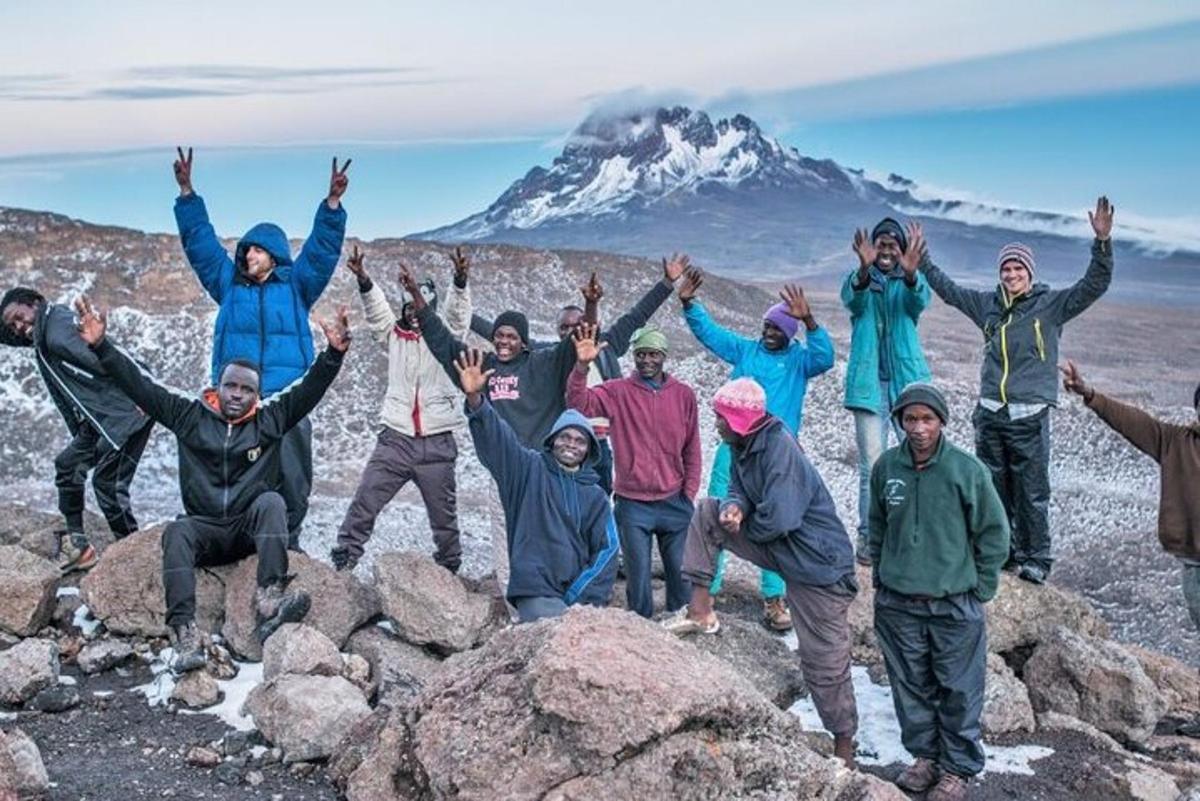 sekumpulan orang berdiri di atas batu di hadapan gunung