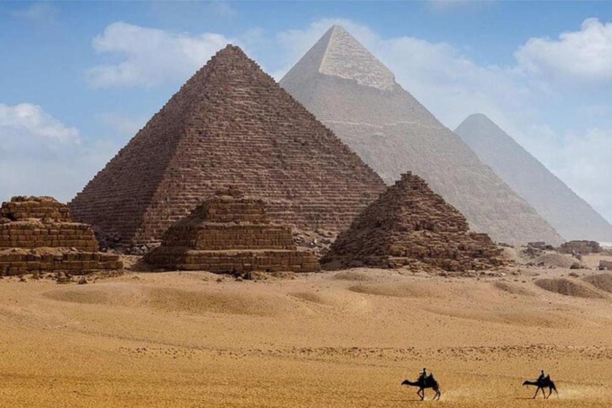 dvaja ľudia jazdiaci na koňoch pred pyramídami