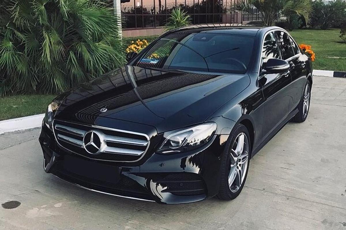 Un automóvil Mercedes Benz negro estacionado en una entrada.