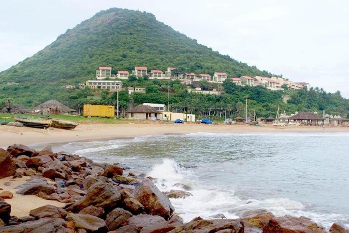 a beach with rocks and a mountain in the background