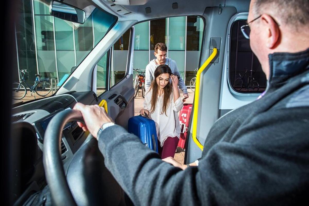 a man driving a bus with a woman with luggage