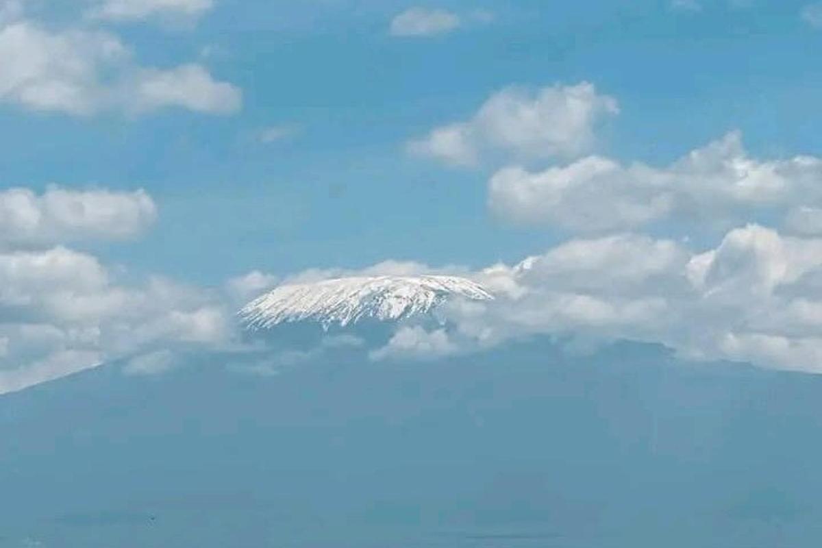 a snow covered mountain in the sky with clouds