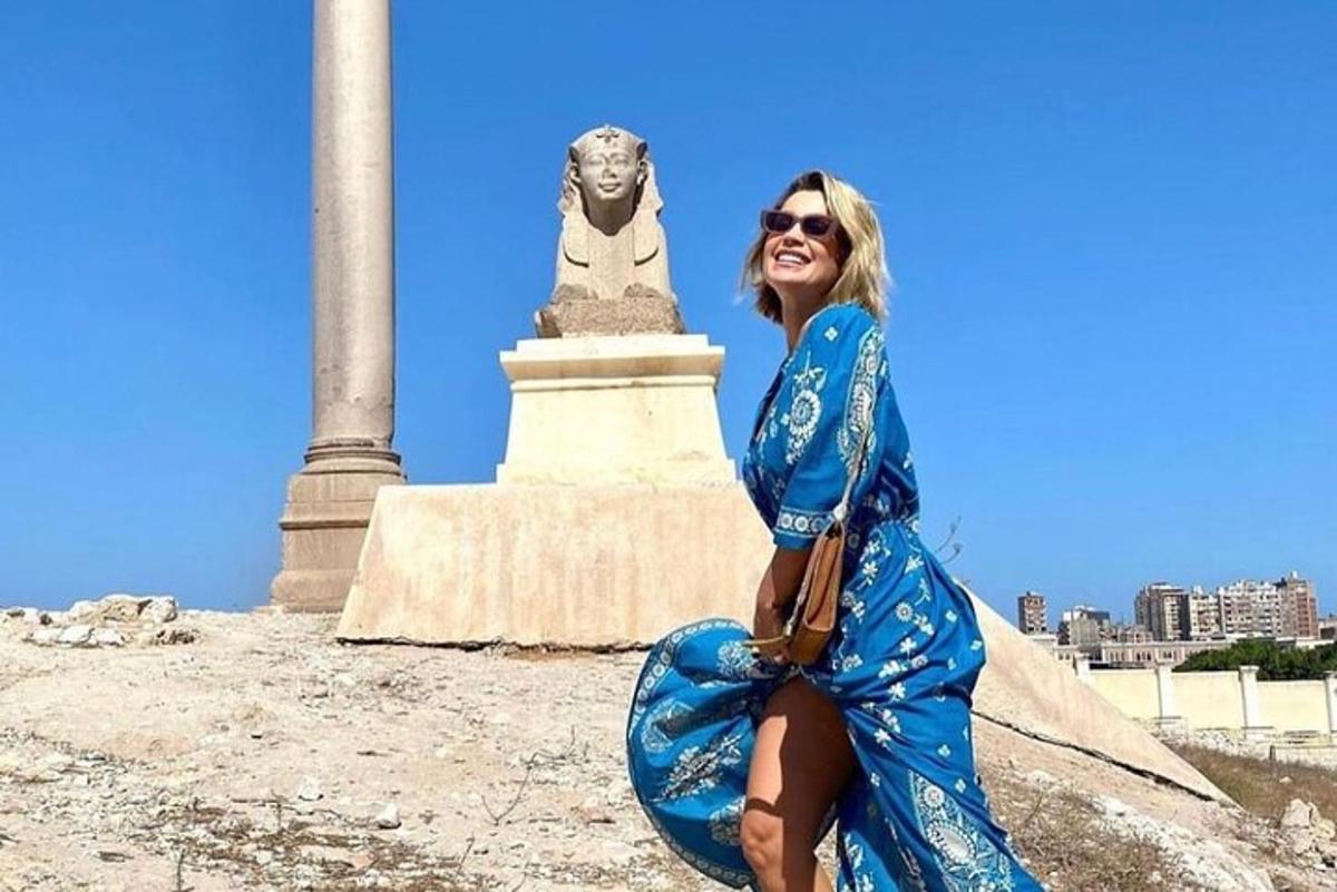 a woman in a blue dress sitting in front of a monument