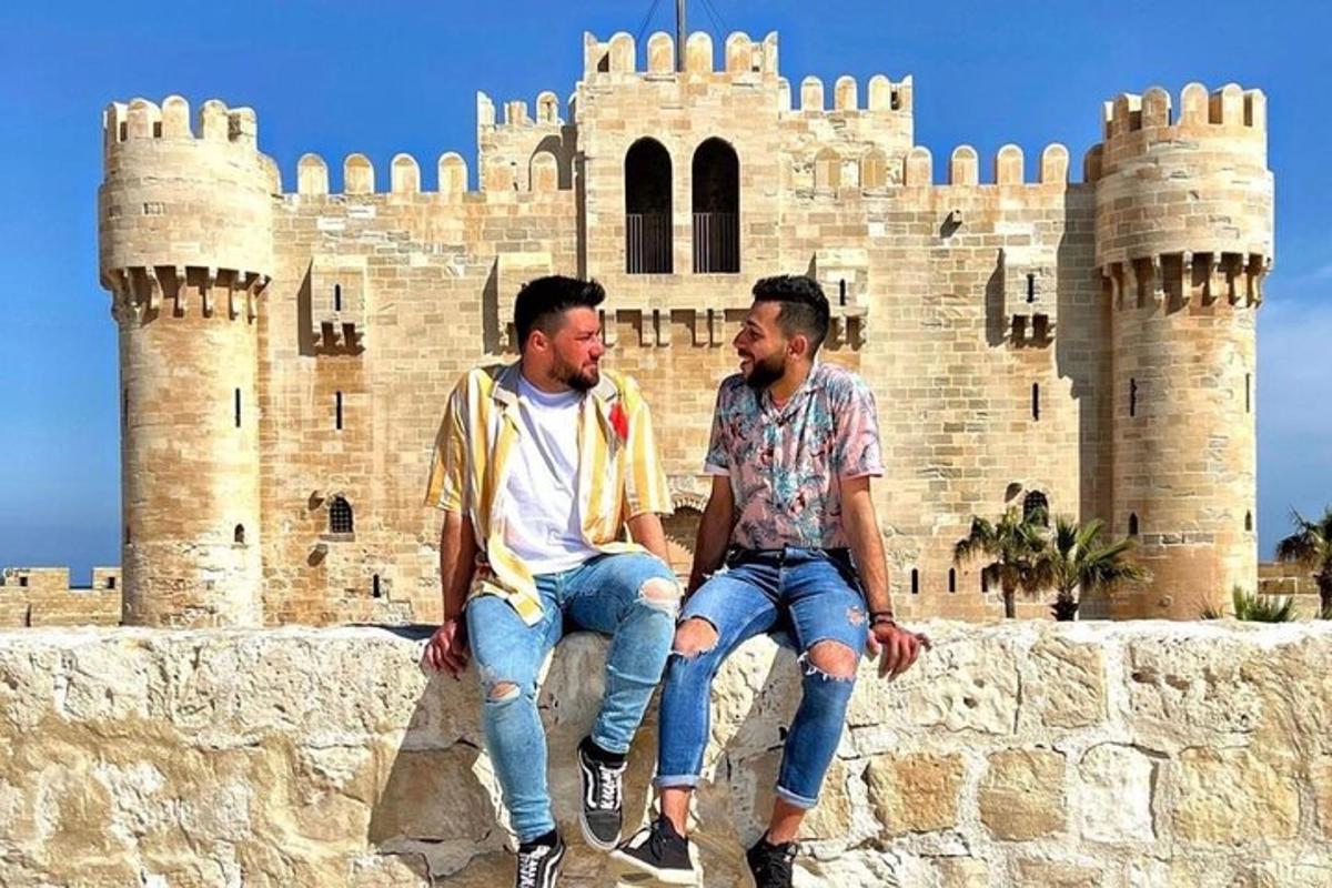 two men sitting on a wall in front of a castle