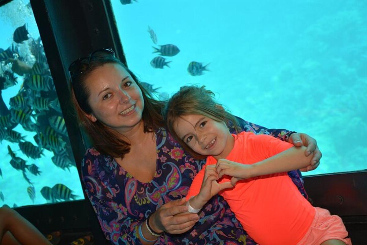 eine Frau und ein kleines Mädchen sitzen neben einem Aquarium