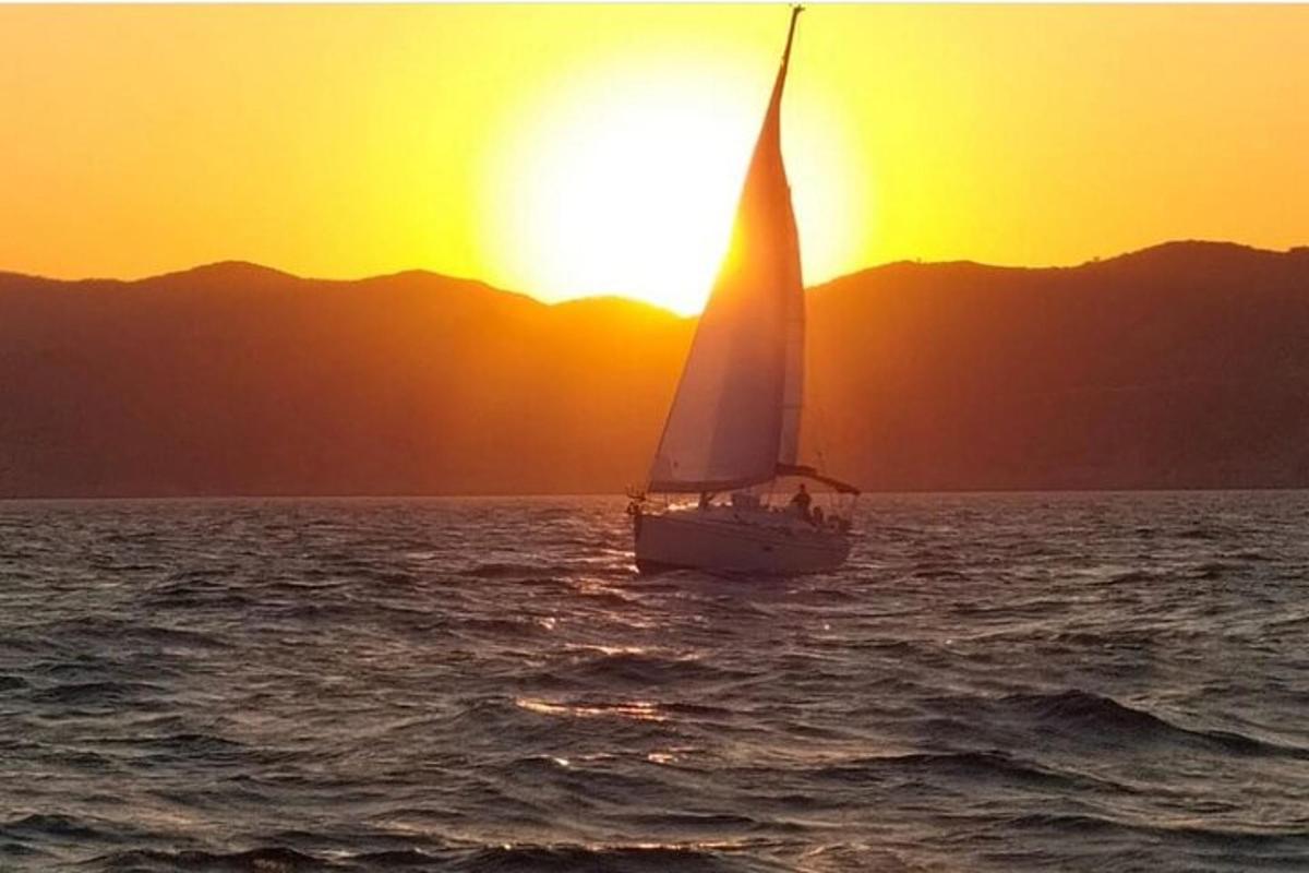 jadrnica v oceanu ob sončnem zahodu