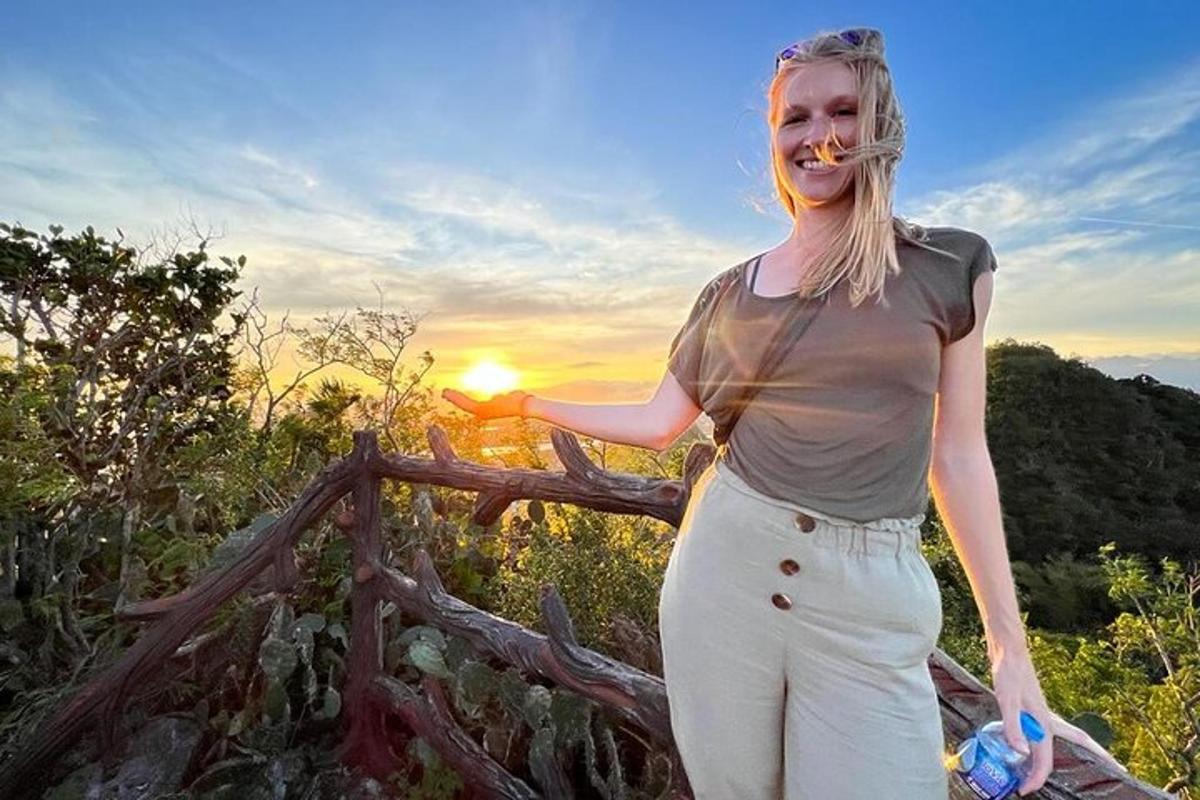 žena stojící vedle plotu se západem slunce v pozadí