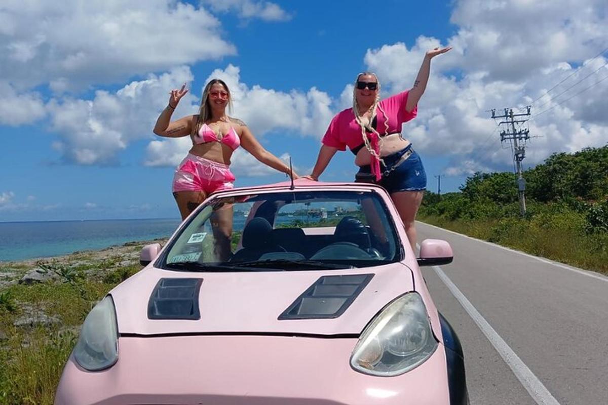 due donne in piedi accanto a un'auto rosa su una strada