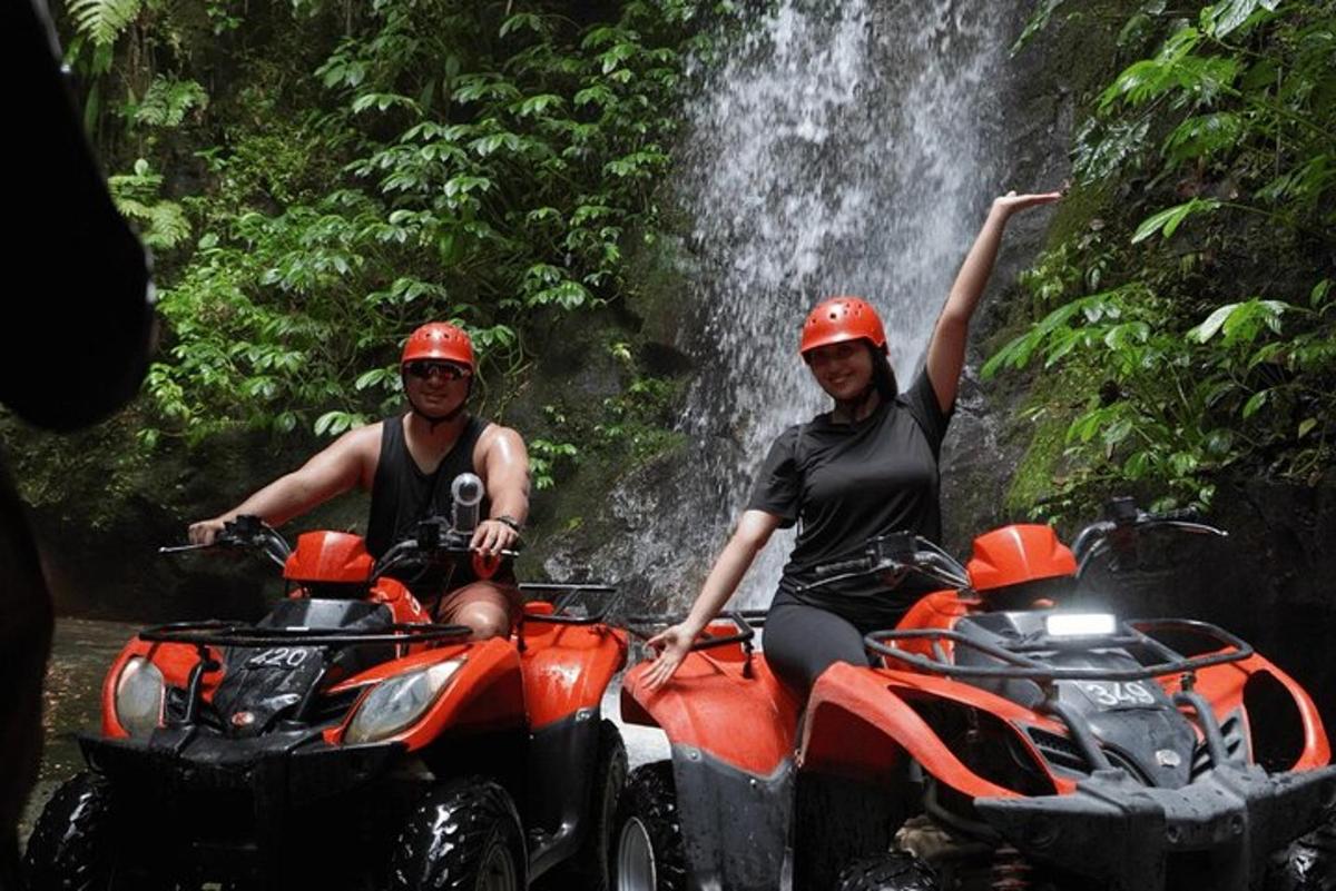 Δύο άτομα σε ATV μπροστά από έναν καταρράκτη